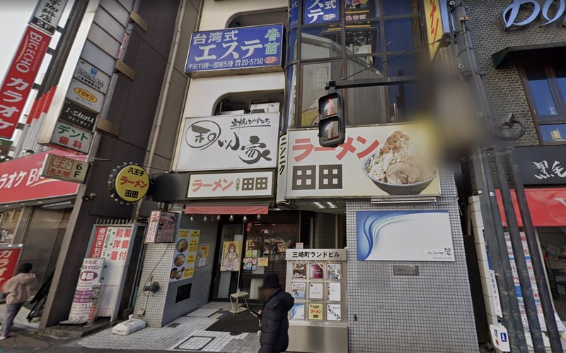 八王子市三崎町の三崎町ランドビル外観。1階入口にラーメン田田の看板、上層階にわんさか家や台湾式エステ春苗、左端にビッグエコーの看板があり、入口脇にテナント案内板が置かれている