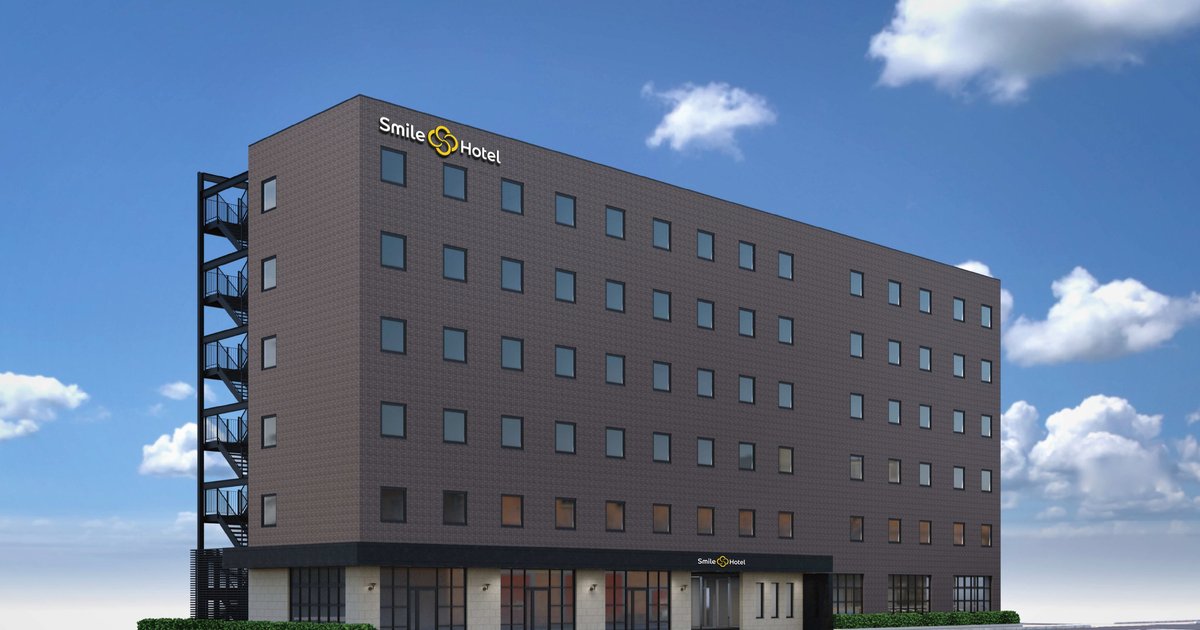 青空の下に立つダークグレーの7階建てホテル外観パース。屋上にSmile Hotelの白い文字と黄色いマーク、1階入口のひさしにも同ロゴ、左側に黒い非常階段がある