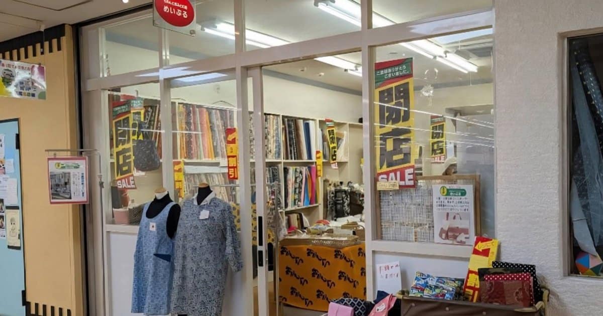 ガラス戸の生地店。赤い看板にめいぷる、黄色い垂れ幕に閉店とSALEと書かれている