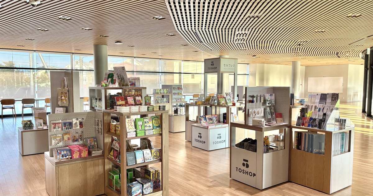ガラス張りの明るい館内に本や雑貨の陳列台が並ぶTOSHOP 桑都の杜の売り場。手前の台にTOSHOPのロゴがある