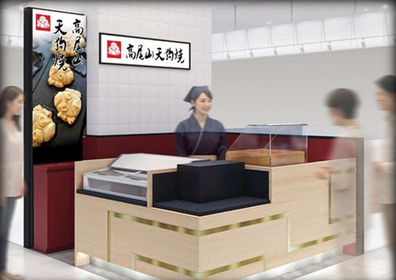 セレオ八王子内の天狗焼の店舗イメージ図。高尾山天狗焼の看板と天狗焼の写真入りの縦長サインがあり、木目調のカウンターの奥に紺色の作務衣姿の店員が立っている