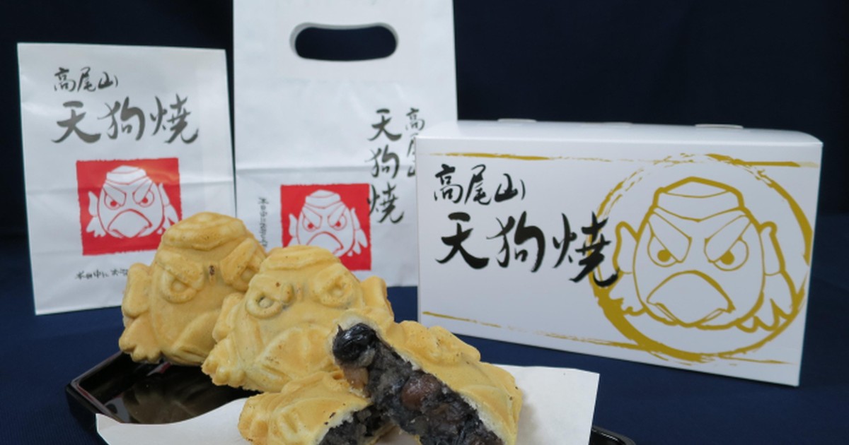 天狗の顔をかたどった焼き菓子の天狗焼と、高尾山天狗焼と書かれた紙袋と白い箱