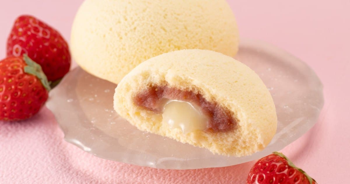 ピンクの背景に黄色いムーンケーキと赤い苺。半分に切った断面に苺カスタードと練乳が見える